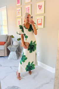 Woman wearing a floral dress in a home setting with decor elements.