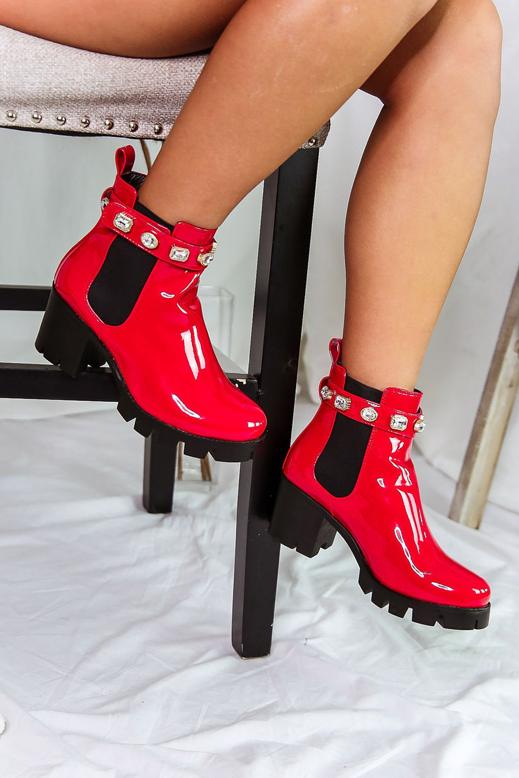 These ankle booties have a treaded sole, chunky heel, elastic side panels, and faux leather strap adorned with jewels.